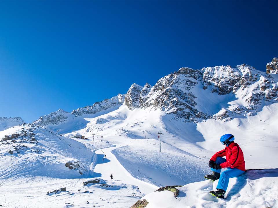 sciatore con attrezzatura noleggiata da noleggio Delpero che osserva le piste del passo Tonale