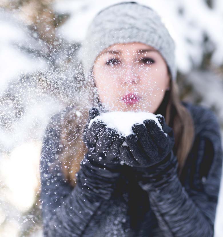 Ragazze vestita da negozio Delpero che soffia la neve